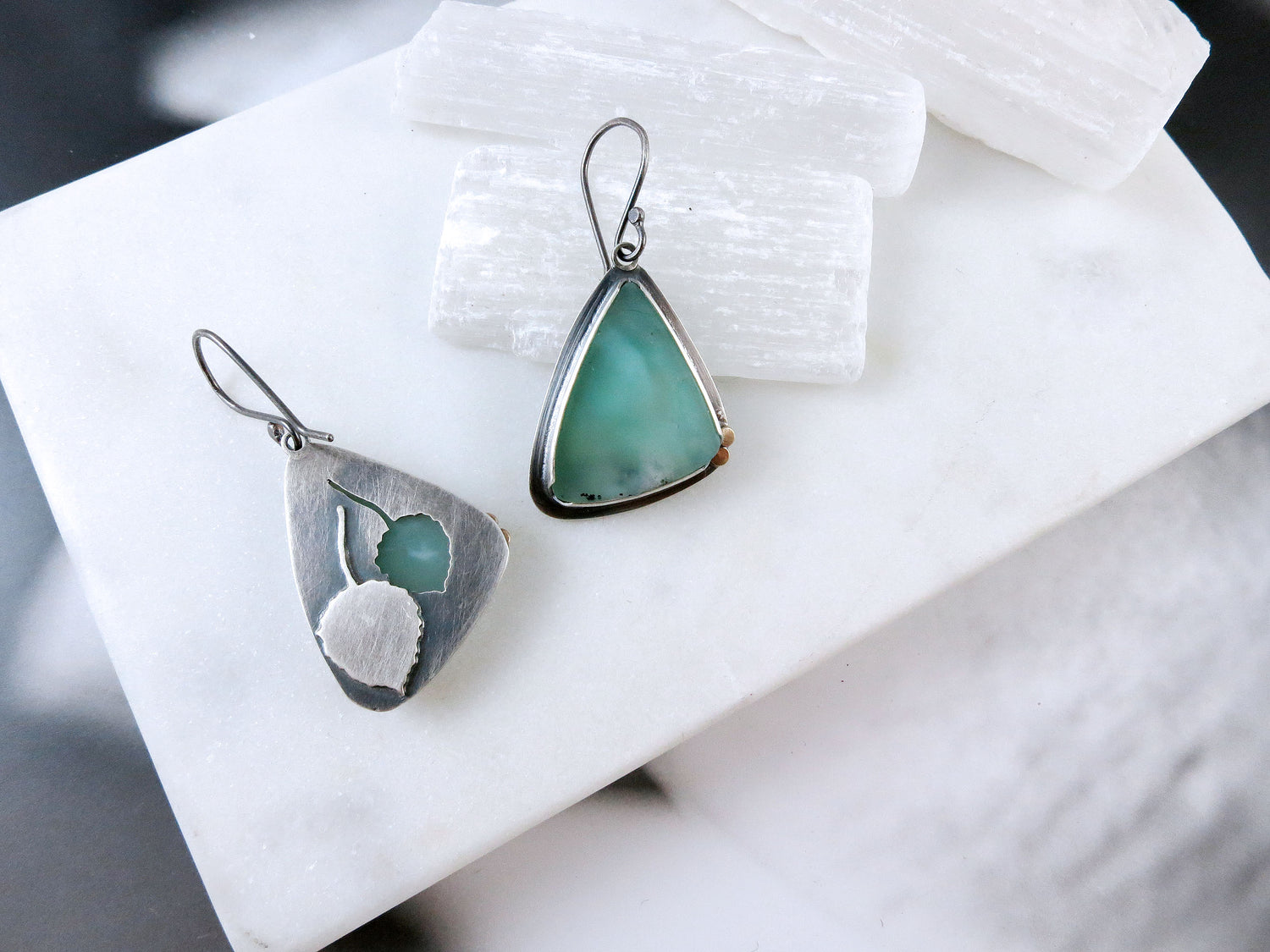 A pair of earrings with seafoam green stones - chrysoprase - set in sterling silver. On the reverse of the earrings are cutouts of Aspen leaves.